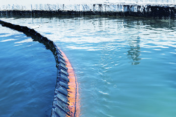 Oil spill. Environmental disaster. A containment boom is a temporary floating barrier used to contain an oil spill.