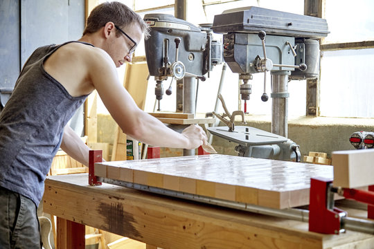 Side view of carpenter applying glue on wooden plank in workshop