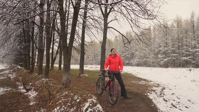 The woman costs with bicycle of a pn a background of the avenue from trees. The hostess walks the dog. Avenue in the countryside. Nature
