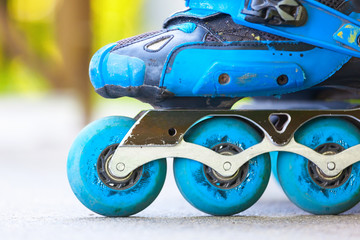 Closeup of inline roller skates with blue wheels.