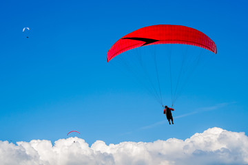 The paraglider hovers in the sky high above the clouds