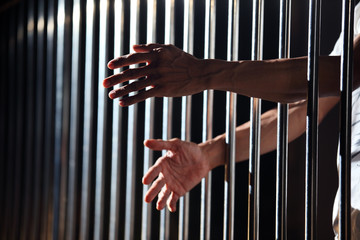 Obraz premium hands of prisoner in jail as background.