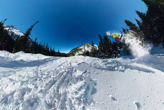 Snowboarder freerider jumping from snow ramp. Wide-angle aerial panorama