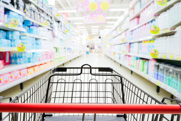 Shopping trolley in supermarket with blured supermarket aisle and shelves background