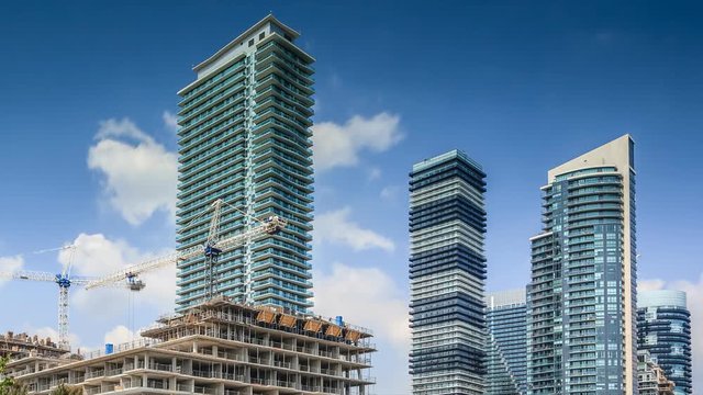 Timelapse of constraction site and residential high rise buildings with moving white clouds in blue sky, Toronto 