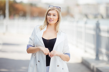 Beautiful blonde young woman on the embankment in the city