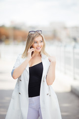 beautiful young woman talking on the phone in the city walking on embankment