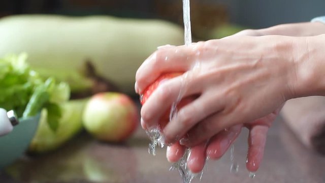 Washing an apple in the kitchen, human hands holding a fresh apple.