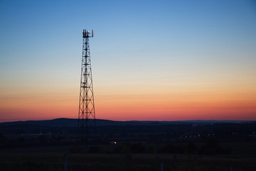 Sunset behind the transmitter. Mobile phone transmitter in the evening. Twilight of clear sky. 