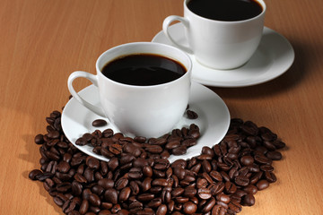 Coffee beans and a white cup on wooden table