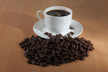 Coffee beans and a white cup on wooden table