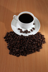 Coffee beans and a white cup on wooden table