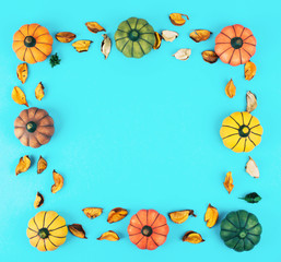 Decorative pumpkins on trendy blue background with fall leaves frame.