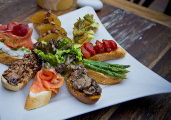 Assorted Spanish tapas served on a ceramic plate over rustic wood—top view ideal for editorial use and Mediterranean food branding.