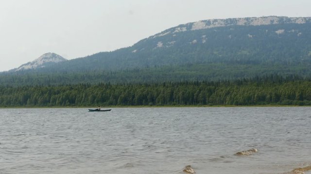 Man rowing oars in a boat in the middle of the lake