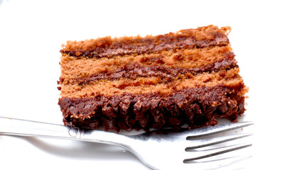 Chocolate cake slice with fork on white background