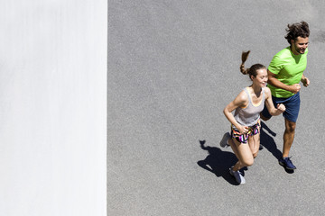 Handsome man and beautiful woman jogging together on street