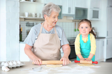 Obraz na płótnie Canvas Cute little girl and her grandmother on kitchen