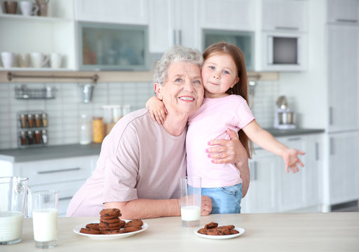 Cute little girl and her grandmother with cookies on kitchen