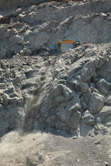 Stones digging using excavator at road construction site in mountain area