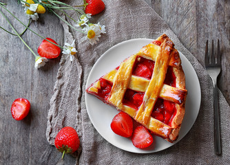 Plate with delicious piece of strawberry pie on wooden table