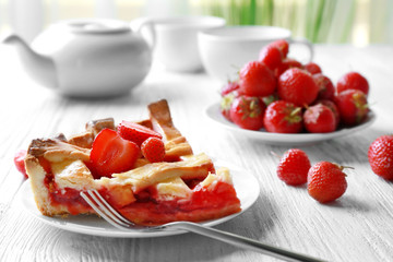 Plate with delicious piece of strawberry pie on wooden table