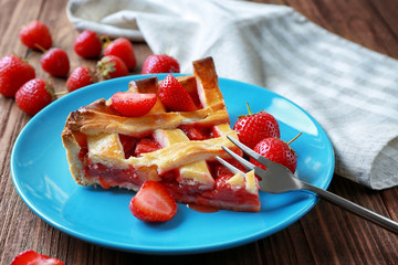 Plate with delicious piece of strawberry pie on wooden table