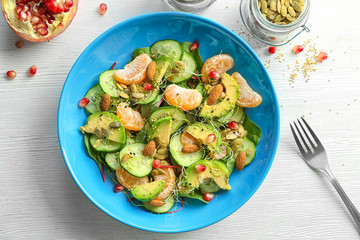 Superfood salad with avocado, tangerine and almond on light background, top view