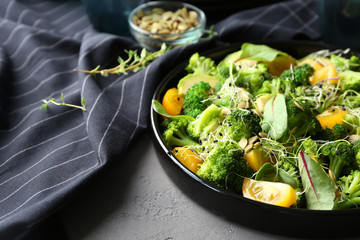 Superfood salad with broccoli and yellow tomato on grey background