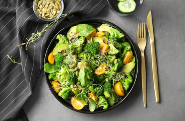 Superfood salad with broccoli and yellow tomato on grey background