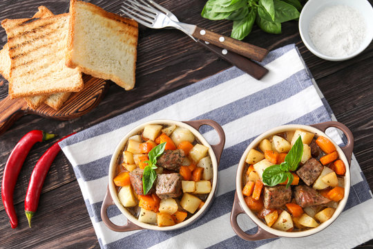 Casseroles with tasty meat and potatoes on table
