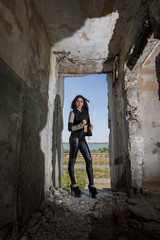 Young girl wearing leather jacket and pants posing in an old building
