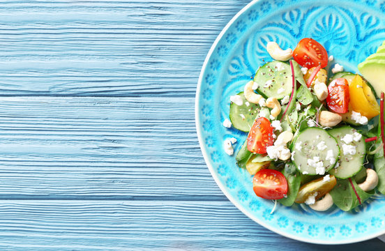 Superfood salad with cucumber, yellow and red tomato on blue wooden background