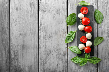 Naklejka na ściany i meble Mozzarella cheese balls, cherry tomatoes and green fresh organic basil on wooden background