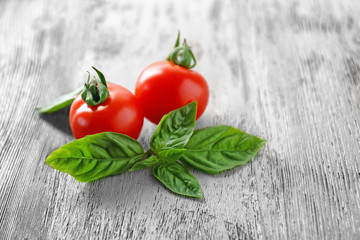 Cherry tomatoes and green fresh organic basil on wooden background
