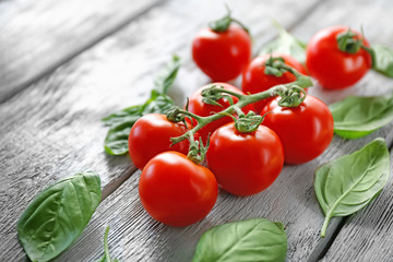 Cherry tomatoes and green fresh organic basil on wooden background