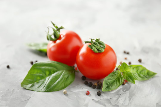 Cherry tomatoes and green fresh organic basil on grey background