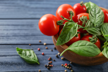Cherry tomatoes and green fresh organic basil on wooden background