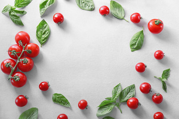 Fototapeta na wymiar Composition with cherry tomatoes and green fresh organic basil on light background