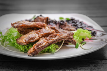 Delicious ribs served with sauce and salad on dinner table