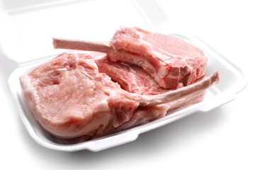 Raw ribs in container on white background