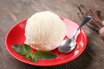 Plate with delicious vanilla ice cream on wooden background