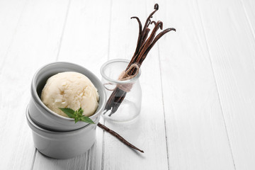 Delicious vanilla ice cream in ceramic bowl on white wooden background