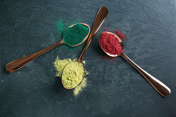 Fototapeta na wymiar Various colorful superfood powders in spoons on color background