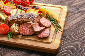 Tasty meat with vegetables on wooden board