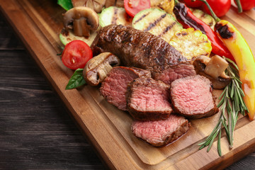 Tasty meat with vegetables on wooden board