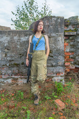 girl with gun posing standing at a concrete wall.