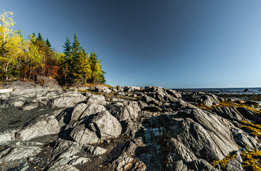 rocks and forest in autumn colors on the shore of the St. Lawrence River in Bic Park at low tide
