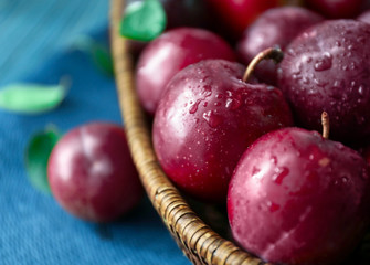 Wicker bowl with fresh ripe plums, closeup
