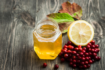 Honey, lemon and berries on wooden table. Homemade cold and flu remedies. Selective focus, space for text.